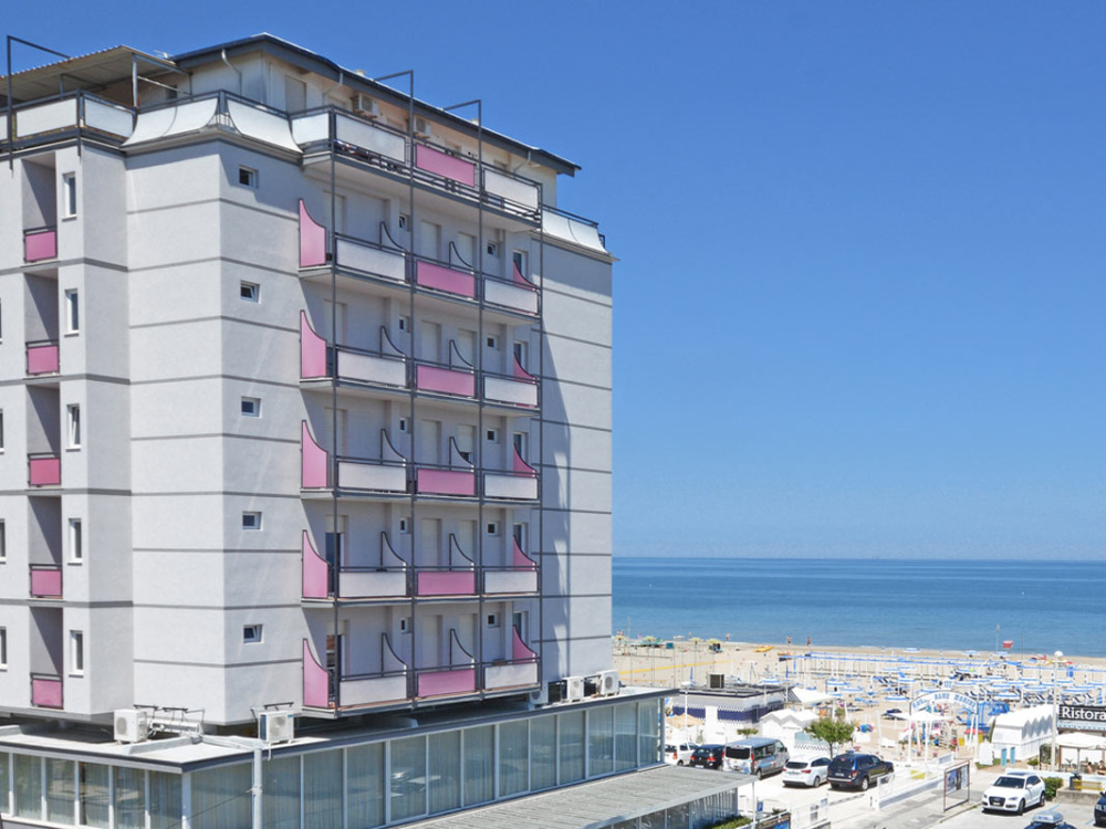 Hotel fronte mare con balconi rosa e vista sulla spiaggia e il mare.