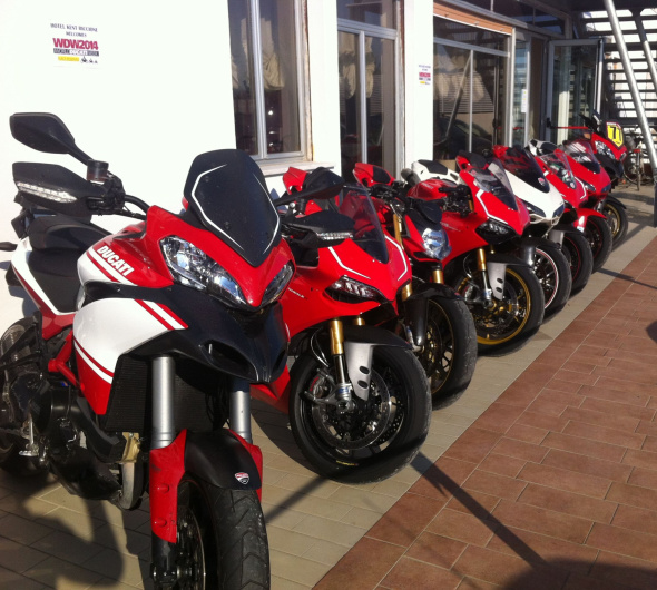 Fila di moto Ducati rosse parcheggiate davanti a un edificio.