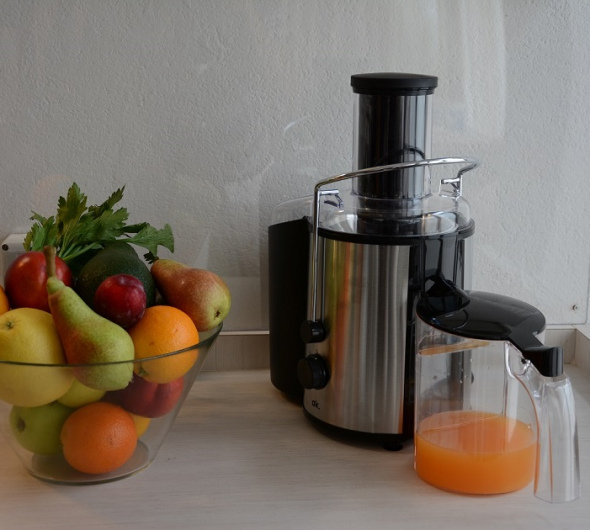 Centrifuga con ciotola di frutta fresca e succo d'arancia appena spremuto.