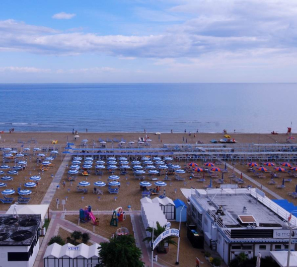 Spiaggia con ombrelloni colorati, mare calmo e cielo parzialmente nuvoloso.