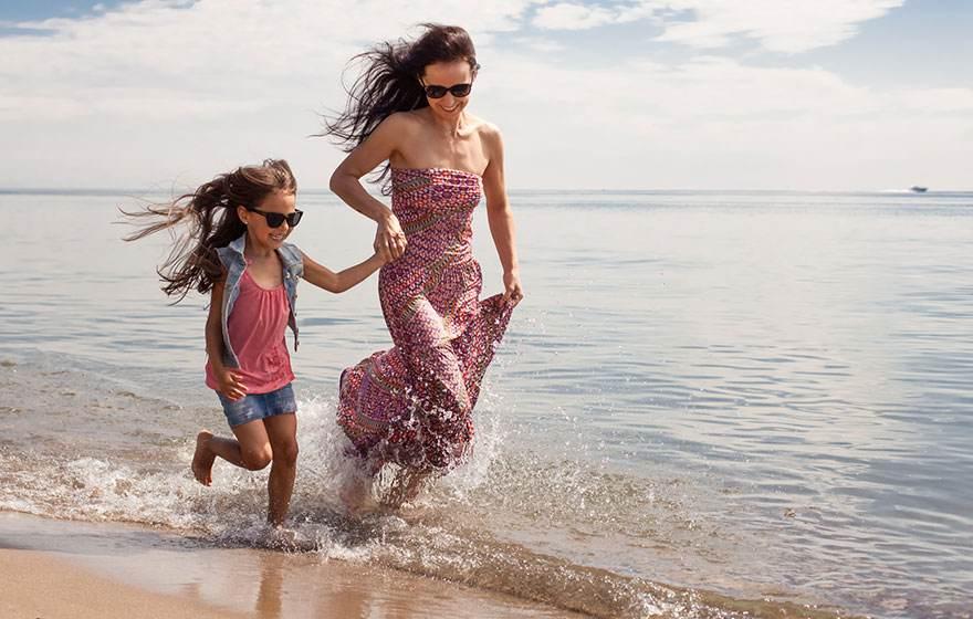 Mother and daughter run joyfully on the beach.